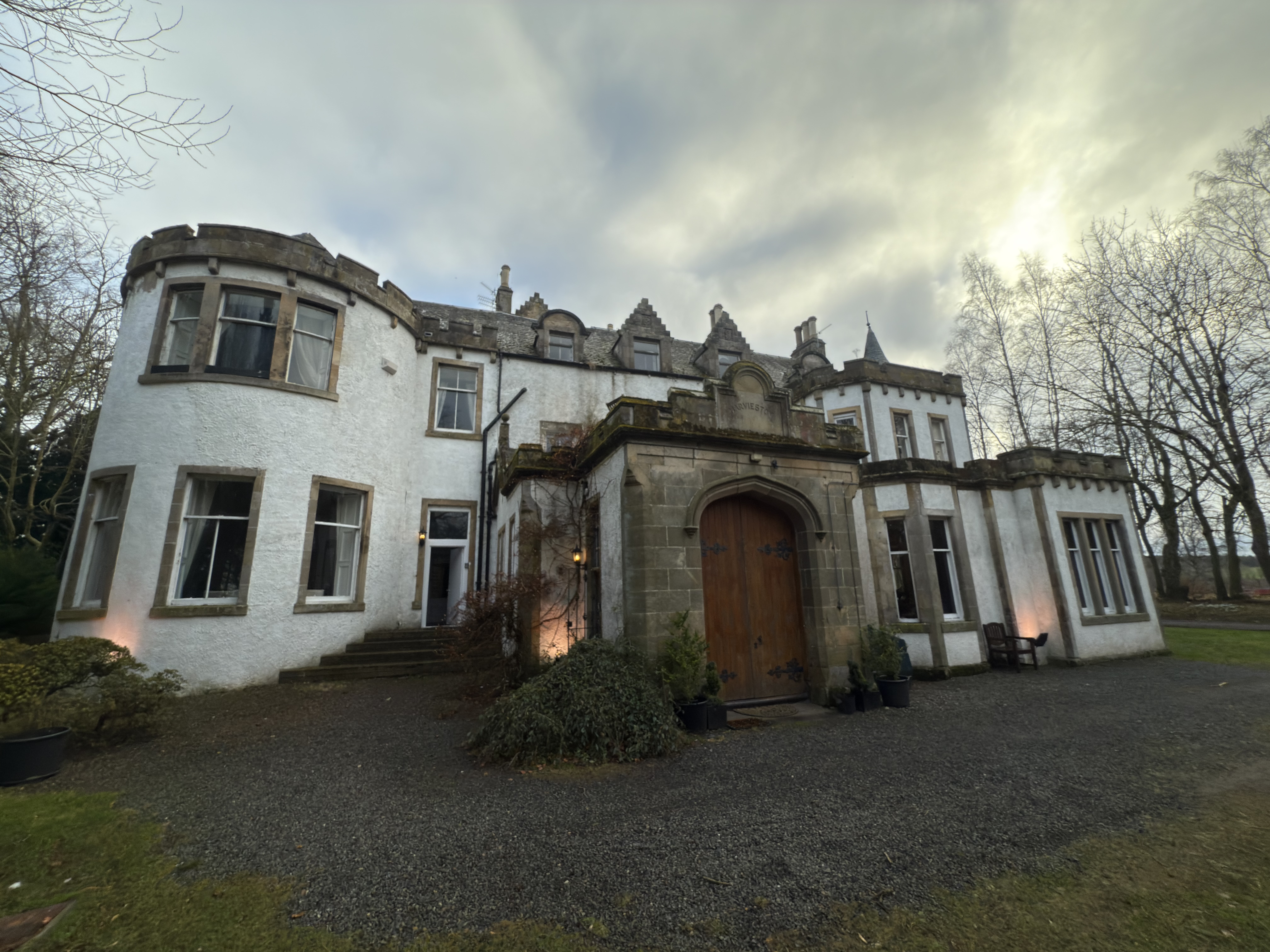 Close view of Harvieston Hall with stone entrance and mature trees