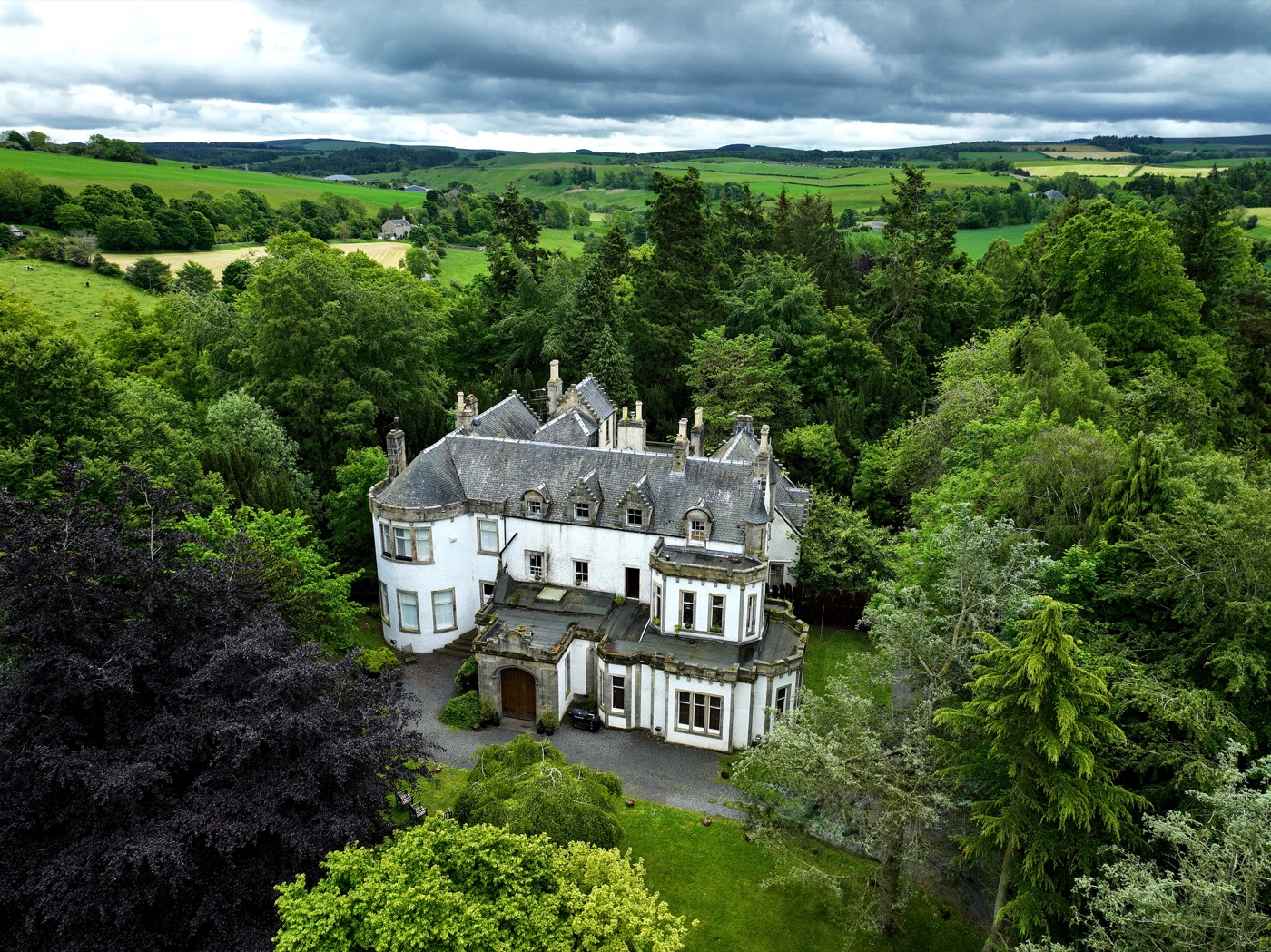 Harvieston Hall seen from above with surrounding trees and Scottish countryside